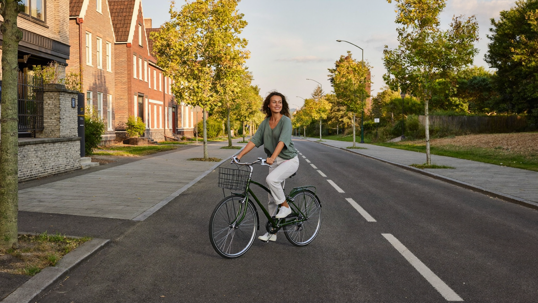 Een vrouw van eind twintig fietst ontspannen door een rustige woonstraat in de late middag, op weg naar huis