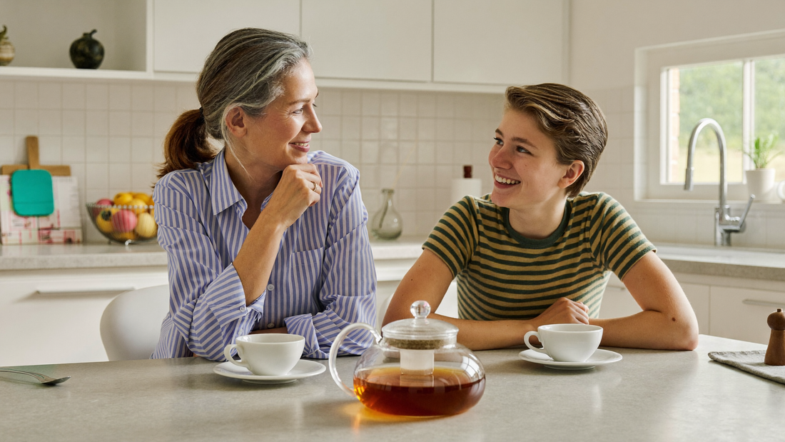 Een moeder en haar zoon van rond de achttien zitten samen aan de keukentafel en praten rustig met elkaar