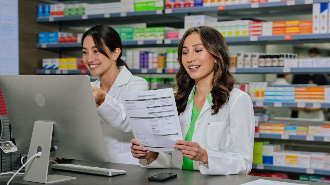Een vrouw van in de vijftig bespreekt een papieren schema met haar apotheker aan de balie