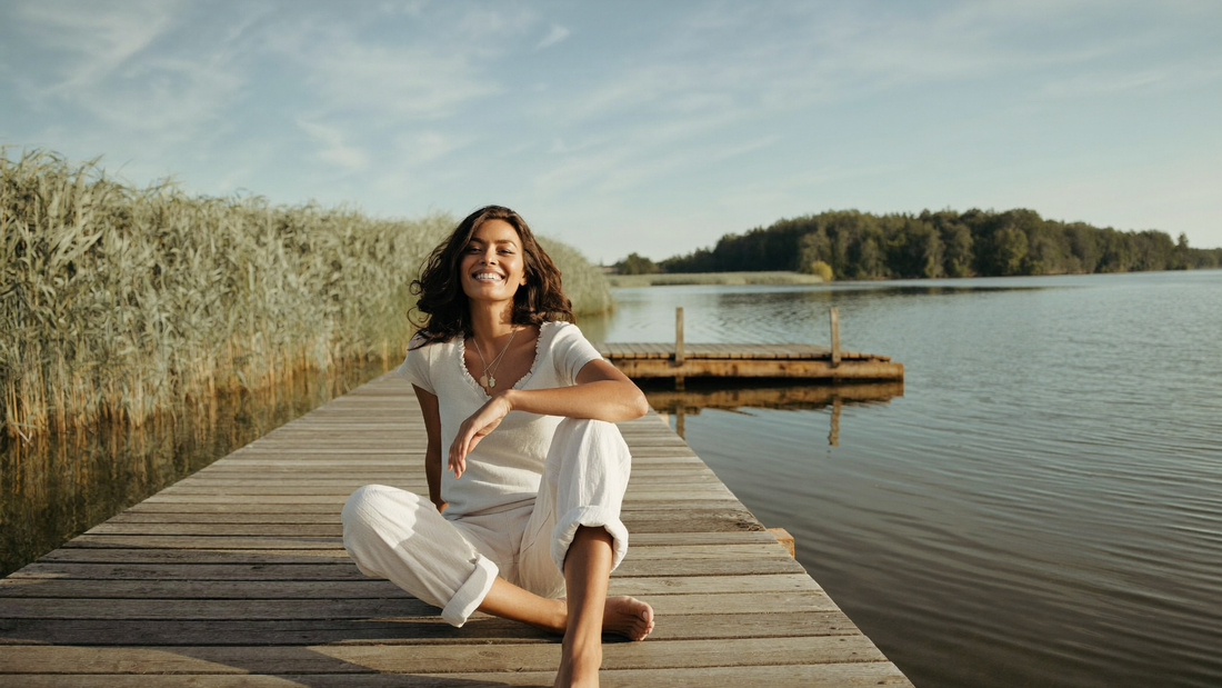 Iemand zit ontspannen op een steiger aan het water in de ochtendzon