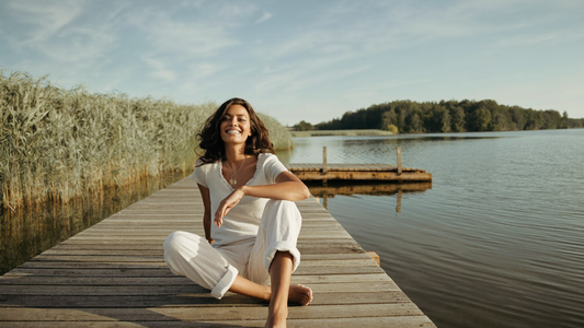 Iemand zit ontspannen op een steiger aan het water in de ochtendzon