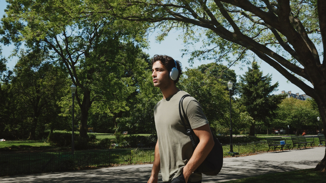 Een jonge man van in de twintig wandelt uitgerust op een zonnige zondagochtend door een stadspark met groene bomen